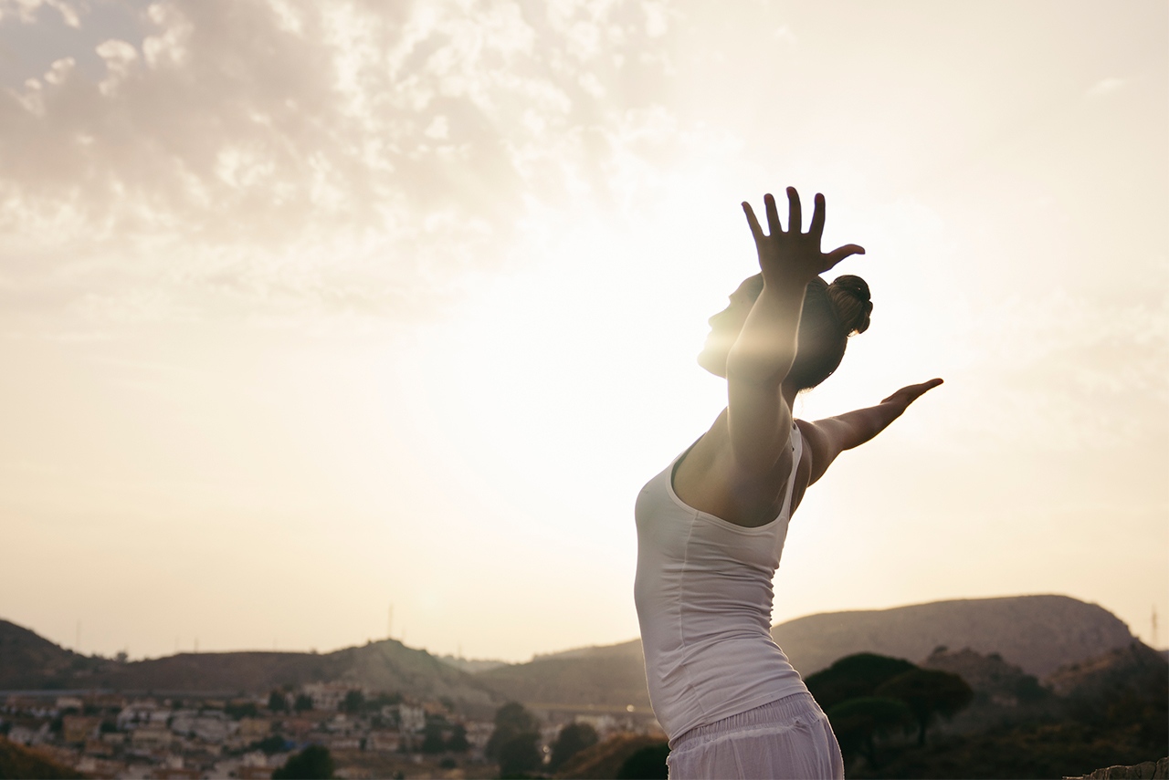 Mulher alonga o corpo enquanto olha para o horizonte