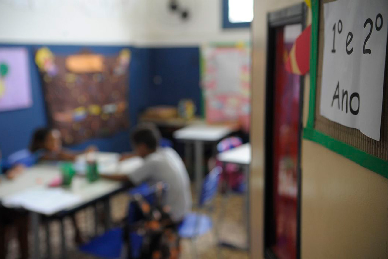 Sala de aula de ensino fundamental com crianças sentadas e desenvolvendo trabalho em grupo